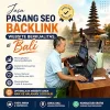 Seorang pria bekerja di depan dua laptop dengan latar belakang pura Bali untuk layanan jasa pasang backlink SEO.